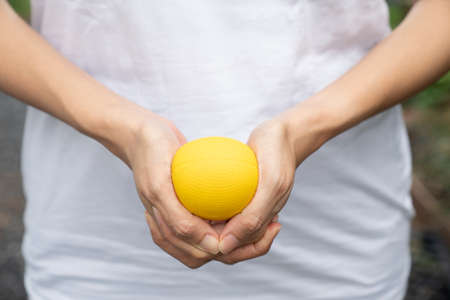 Hands of a woman squeezing a yellow stress ball, close upの写真素材