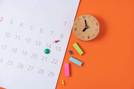 close up of calendar and alarm clock on the orange table background, planning for business meeting or travel planning conceptの写真素材