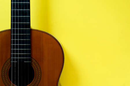 old classic guitar on yellow table background, music conceptの写真素材