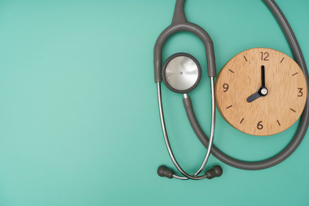Top view of stethoscope and clock on the green background, schedule to check up healthy conceptの写真素材