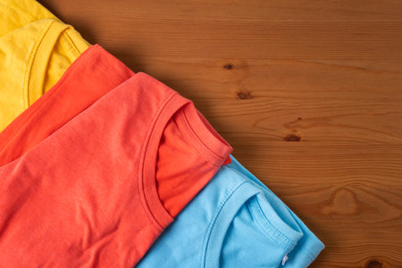 close up of colorful t shirt clothes on wooden table background, travel lifestyle conceptの写真素材