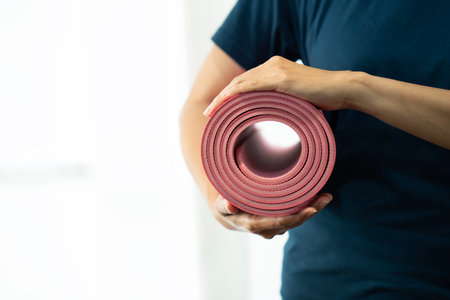 Young woman holding a yoga mat in exercise class for a sport and healthy conceptの写真素材