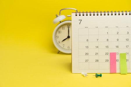 close up of calendar and alarm clock on the yellow table background, planning for business meeting...