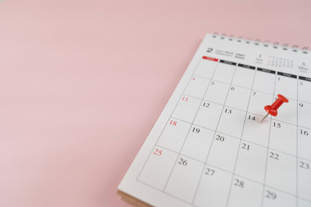 close up of pin on calendar on the pink table background, planning for business meeting or travel planning conceptの写真素材