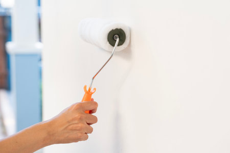 hand worker holding brush painting roller white on the wall house, diy and repair conceptの写真素材
