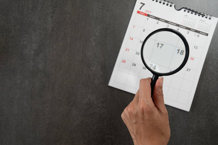 Take a magnifying glass and look at the calendar.の写真素材