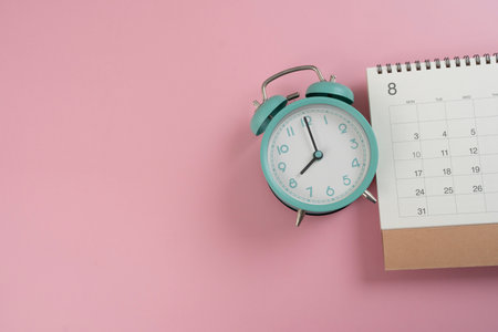 close up of alarm clock and calendar on the pink table background, planning for business meeting or...