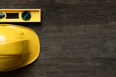 Yellow building level and helmets on the old wood table, engineering eqipment tool concept, top view.の写真素材
