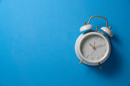 Retro alarm clock with blue background, vintage style.の写真素材