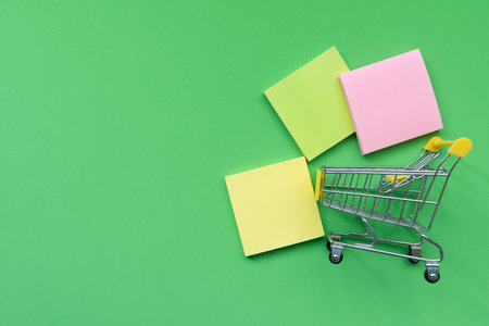 Shopping cart toy on table with green background, Sale buy mall market shop consumer concept. Copy...