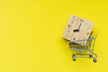 Shopping cart toy on table with yellow background, Sale buy mall market shop consumer concept. Copy spaceの写真素材