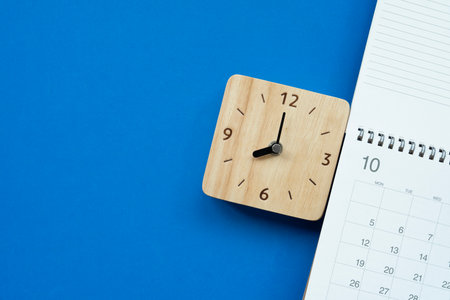 close up of calendar and alarm clock on the blue table background, planning for business meeting or travel planning conceptの写真素材