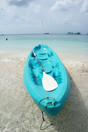Blue kayak on a white sandy beach and blue sky の写真素材
