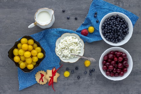 cottage cheese with berries, milk and biscuit for breakfast on the gray backgroundの写真素材
