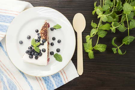 Piece of sweet cake with cherry, blueberry and mint on a plateの写真素材