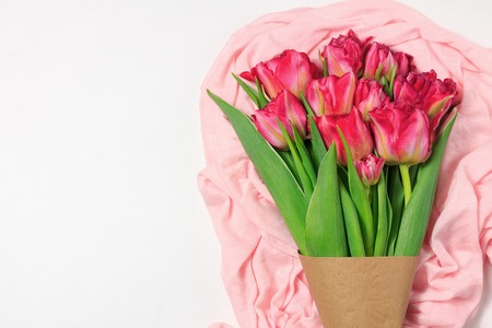 Spring boquet of red and pink tulips on the light pink cloth. Floral white background with space for textの写真素材