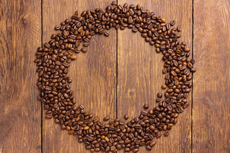 Round of coffee beans on wood background