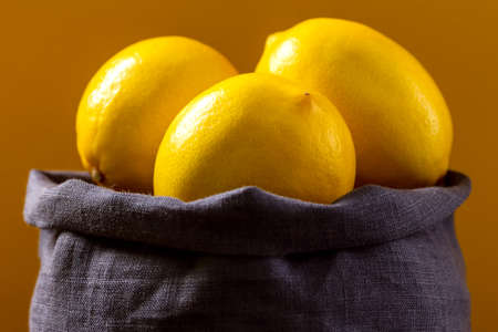 Lemons in blue bag on yellow background. Organic fresh citrus fruits - lemons.の写真素材
