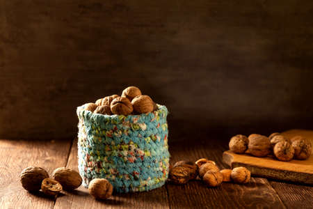 Whole walnuts in wicker basket made of blue fabric on rustic old wooden tableの写真素材