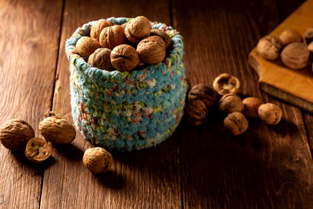 Whole walnuts in wicker basket made of blue fabric on rustic wooden table