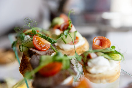 An assortment of elegant canapes with various meat and vegetable toppings on a glass trayの写真素材