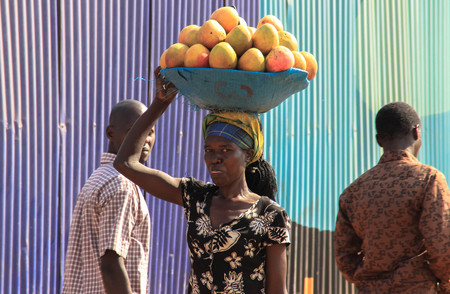 Nairobi, Kenya - January 21, 2018: A mango trader carries goods on her head through the streets of Nairobi and makes facesのeditorial素材