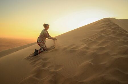 The highest sand dunes in the world at sunset in Namib Desert, in the Namib-Nacluft National Park in Namibia. Sossusvlei. Young woman tourist playing with sandの写真素材