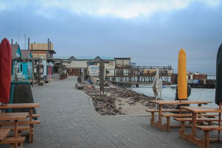 Walvis Bay, Namibia - April 25, 2015: Atlantic coastline with jetty at dusk. Empty restaurant on the...