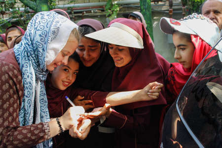 Shiraz, Iran - May 10, 2017: a large group of schools are relaxing in nature. Teenage girls from an Iranian school in school uniforms and hijabs are photographed with a tourist.のeditorial素材
