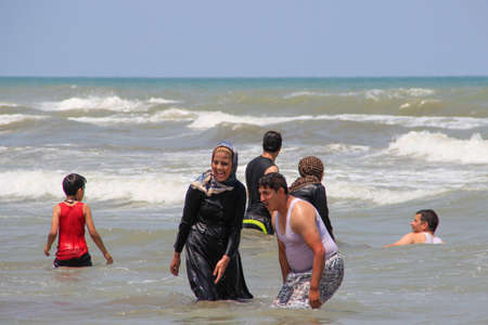 Caspian Sea, Iran - May 25, 2017: people have fun and swim dressed in the sea for the weekend. Muslim women swim in clothes and shawls.のeditorial素材