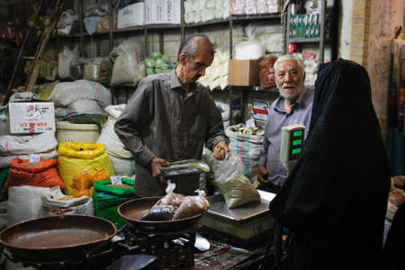 Kum, Iran - May 10, 2017: Famous Iranian market (bazaar) and a woman in a black chodor buy productsのeditorial素材