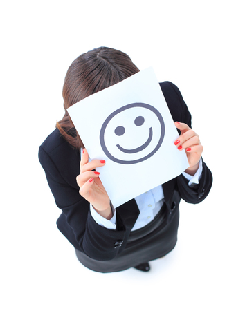 A beautiful young business woman hiding behind a smiley face の写真素材