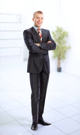 Young smiling business man standing in a light and mordern business hall  の写真素材