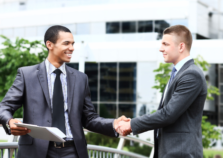 two cheerful businessman handshaking in conference hallの写真素材