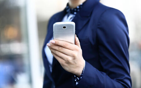 Young beautiful woman writes an SMS to your mobile phoneの写真素材