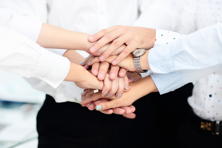 International business team showing unity with their hands together in office