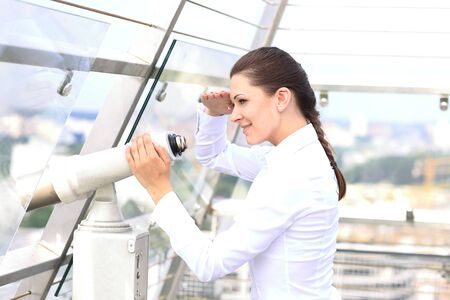 Caucasian woman looking through binoculars over the cityの写真素材