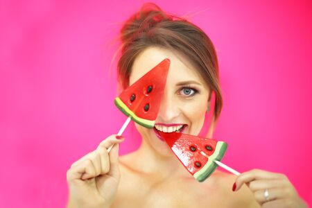 Studio closeup colorful portrait of young sexy funny fashion girl posing on pinkwall background in summer style outfit with red lollipopの写真素材
