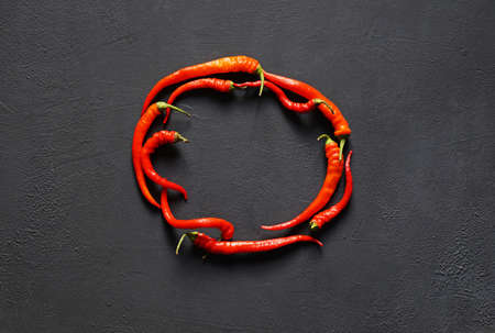 Withered red Chili pepper lie in the shape of a circle on dark background. copy space