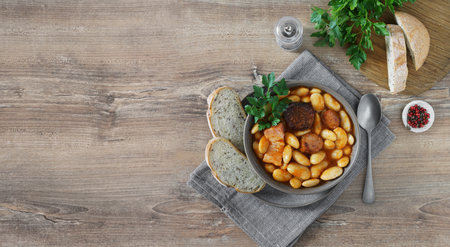 Typical Spanish fabada asturiana on wooden table with bread. Top view, copy spaceの写真素材