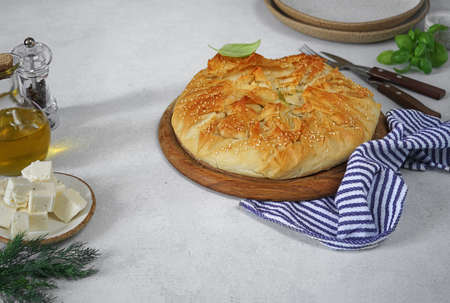 delicious spinach feta cheese pie or spanakopita on wooden desk, white table, authentic recipe,...