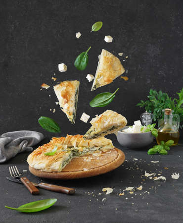 Traditional Greek cuisine. Spanakopita pie and pieces with spinach and feta cheese on dark background.Lavitation foodの写真素材