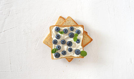 French toast with blueberry is on the white table in the centre. Top view, flat layの写真素材