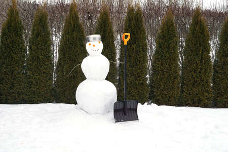 New year snowman from white snow outdoor. Winter activity and party. Happy holiday and celebration. Snowman with shovel.の写真素材