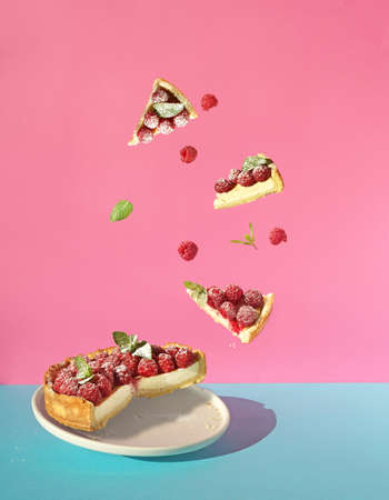 cheesecake with fresh raspberry and flying pieces on blue and pink background, free copy space, levitation conceptの写真素材