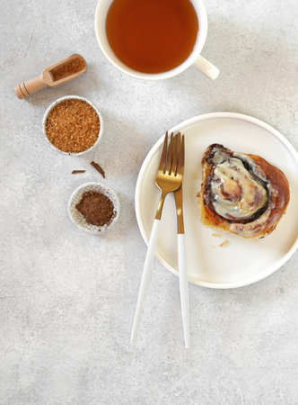 Cinnamon bun with cream on a plate with cup of coffee . Breakfast concept, top view, vertical orientationの写真素材