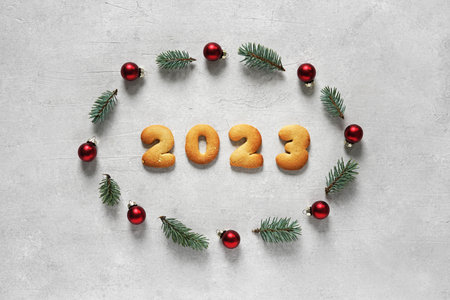 Christmas wreath of pine twig and toys with date 2023 from cookies inside on a light background....