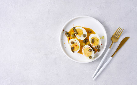 Deviled eggs with paprika, mustard and capers. Appettizer for breakfast or lunch. White background,...