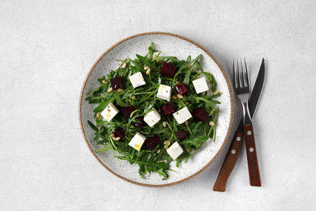 Salad of arugula and beets, pine nuts and with cheese in the bowl. Vegetarian food, top viewの写真素材