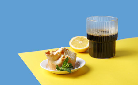Soffioni cake on the plate with a glass of coffe on the yellow and blue background. Breakfast...